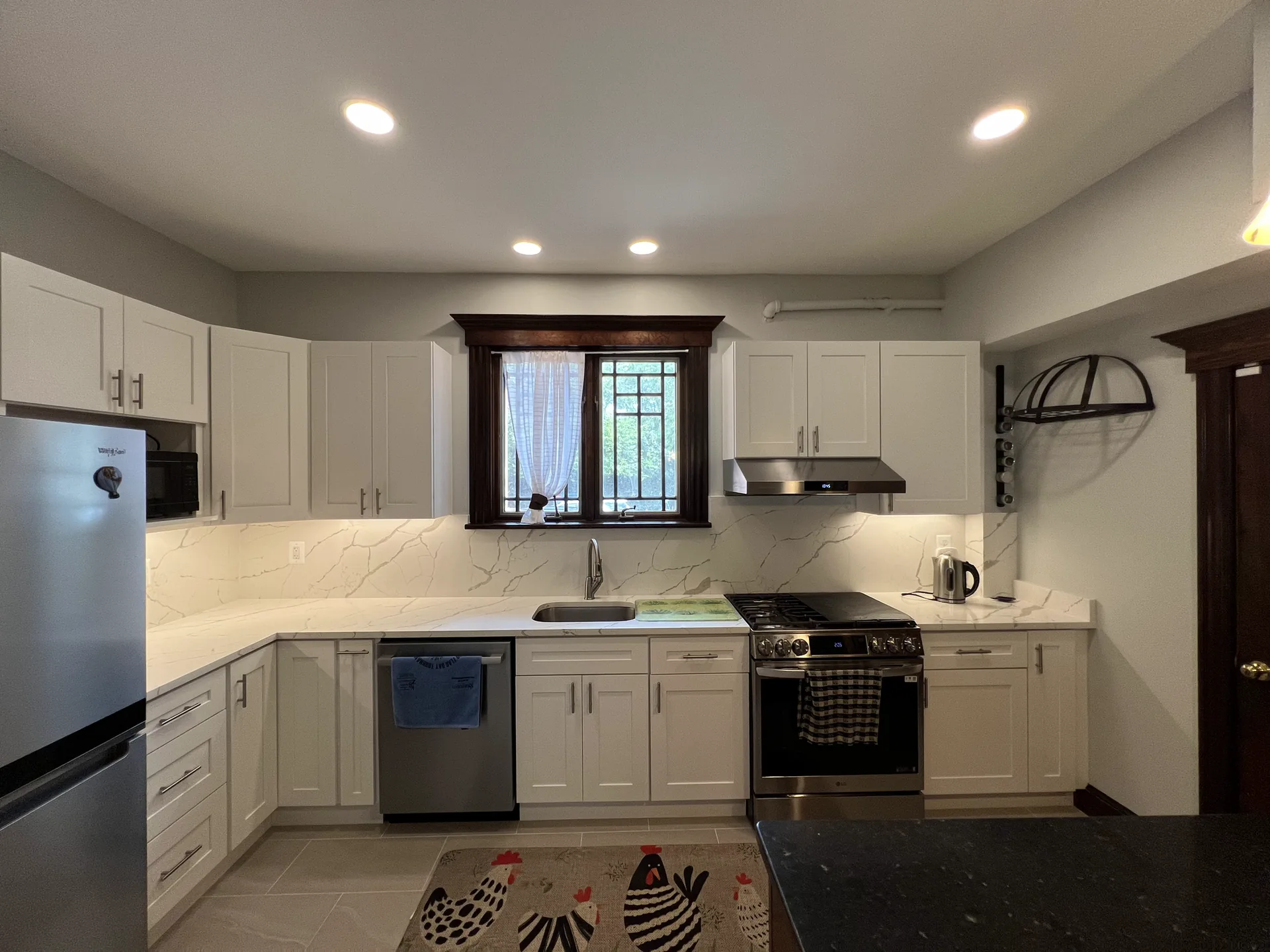 White shaker cabinets around the sink window with a marble-look backsplash and stainless appliances in Arlington, VA