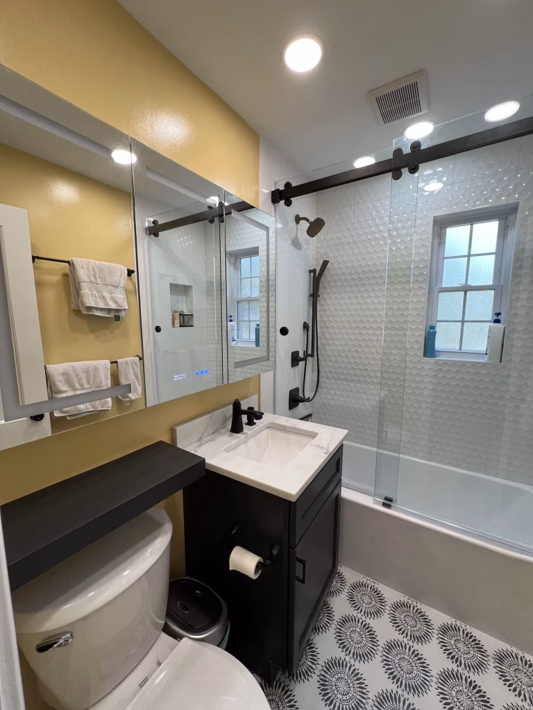 Guest bathroom remodel in Arlington, VA with a charcoal J&K Cabinetry vanity, Questone quartz and frameless sliding glass door by Kitchen & Bath Masters