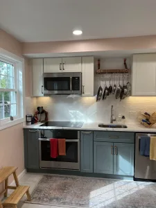 Range wall with sage lower cabinets, white uppers, pot rail and white tile backsplash in Arlington