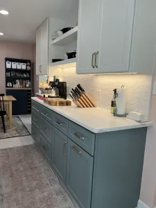 Sage base cabinets, white quartz countertop and under-cabinet lighting in an Arlington kitchen