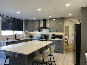 Gray European kitchen with a quartz island, bar stools and stainless refrigerator in Greenbelt, MD