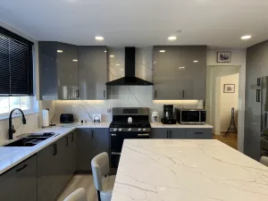 European-style kitchen remodel in Greenbelt, MD with gray frameless Millwork cabinets, black range hood and quartz island by Kitchen & Bath Masters