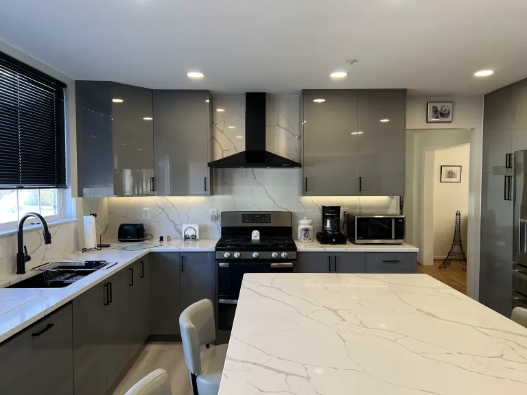 European-style kitchen remodel in Greenbelt, MD with gray frameless Millwork cabinets, black range hood and quartz island by Kitchen & Bath Masters