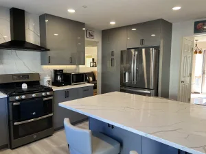 Range wall with black chimney hood, gray cabinets and stainless refrigerator in Greenbelt, MD