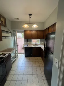 Before photo: dated Washington, DC kitchen with dark wood cabinets, black appliances and beige tile floor