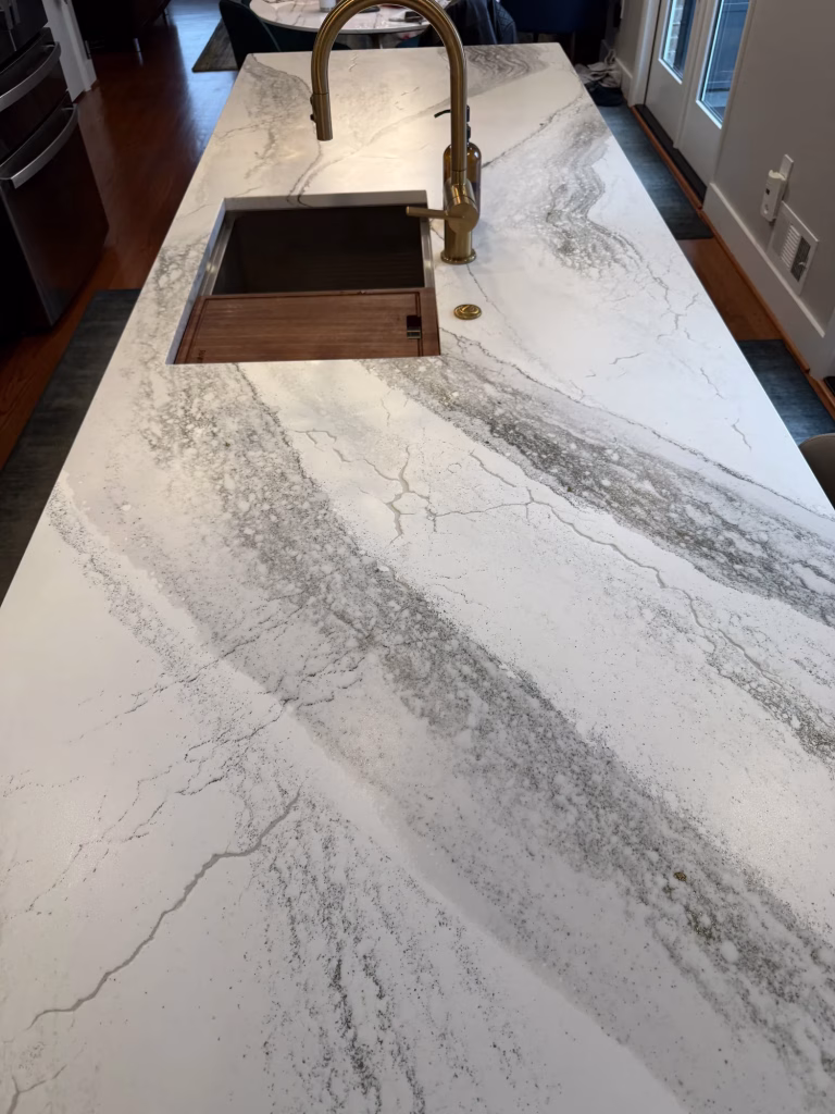Cambria quartz kitchen island with workstation sink and brass faucet in a Silver Spring, MD kitchen remodel by Kitchen & Bath Masters
