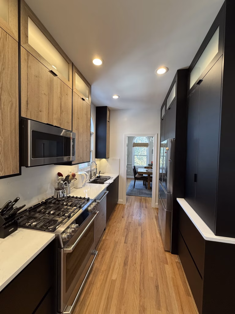 Modern kitchen remodel in Arlington, VA with black flat-panel Millwork custom cabinets, wood-grain uppers and quartz by Kitchen & Bath Masters