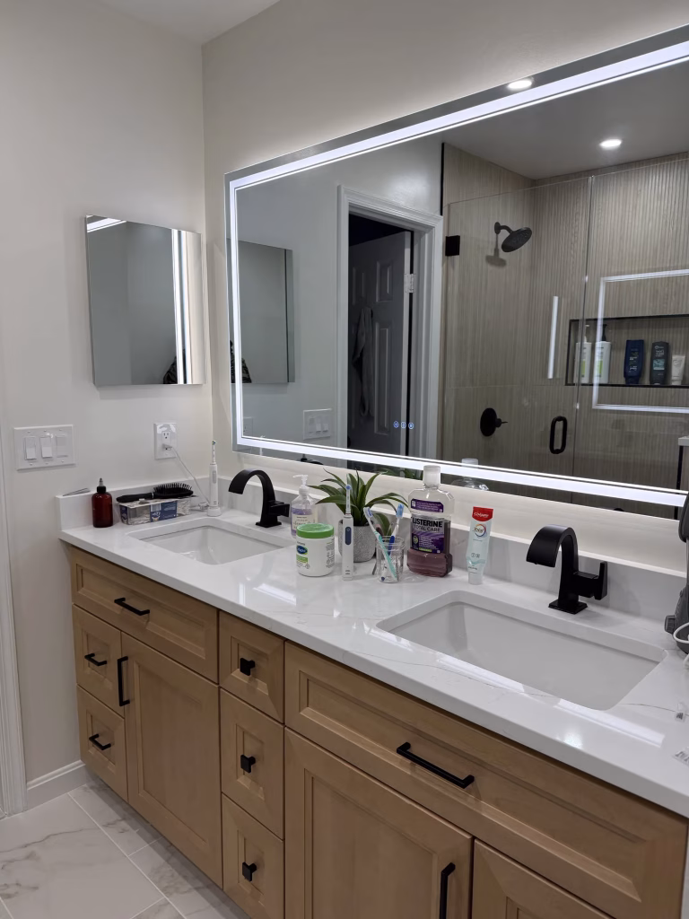 Master bathroom remodel in Arlington, VA with a natural wood double vanity, white quartz and LED mirror by Kitchen & Bath Masters