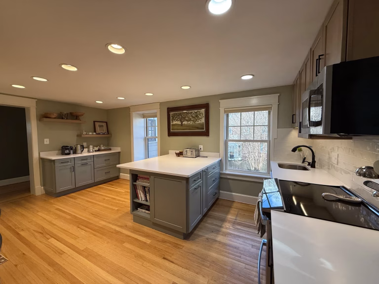 Open-concept kitchen remodel in Arlington, VA with a pistachio green Fabuwood peninsula, built-in book cabinet and Silestone quartz by Kitchen & Bath Masters