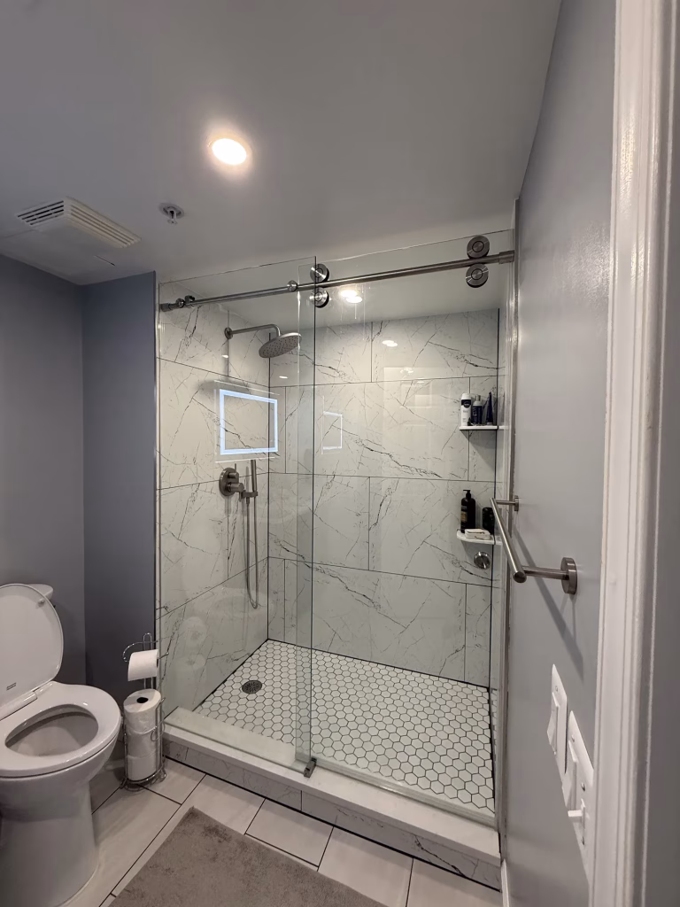 Master bathroom remodel in Arlington, VA with a walk-in shower, marble-look porcelain walls and hex floor tile by Kitchen & Bath Masters