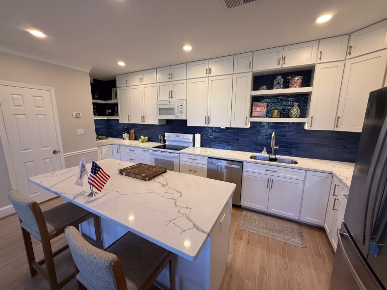 Open-concept kitchen remodel in Arlington, VA with white shaker cabinets, a quartz island and navy blue backsplash tile by Kitchen & Bath Masters
